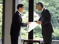 勲章と賞状を受け取り大使と握手を交わす関先生